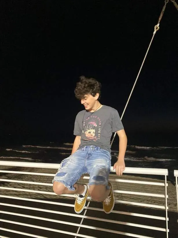עומר יושב על מעקה ליד הים בלילה