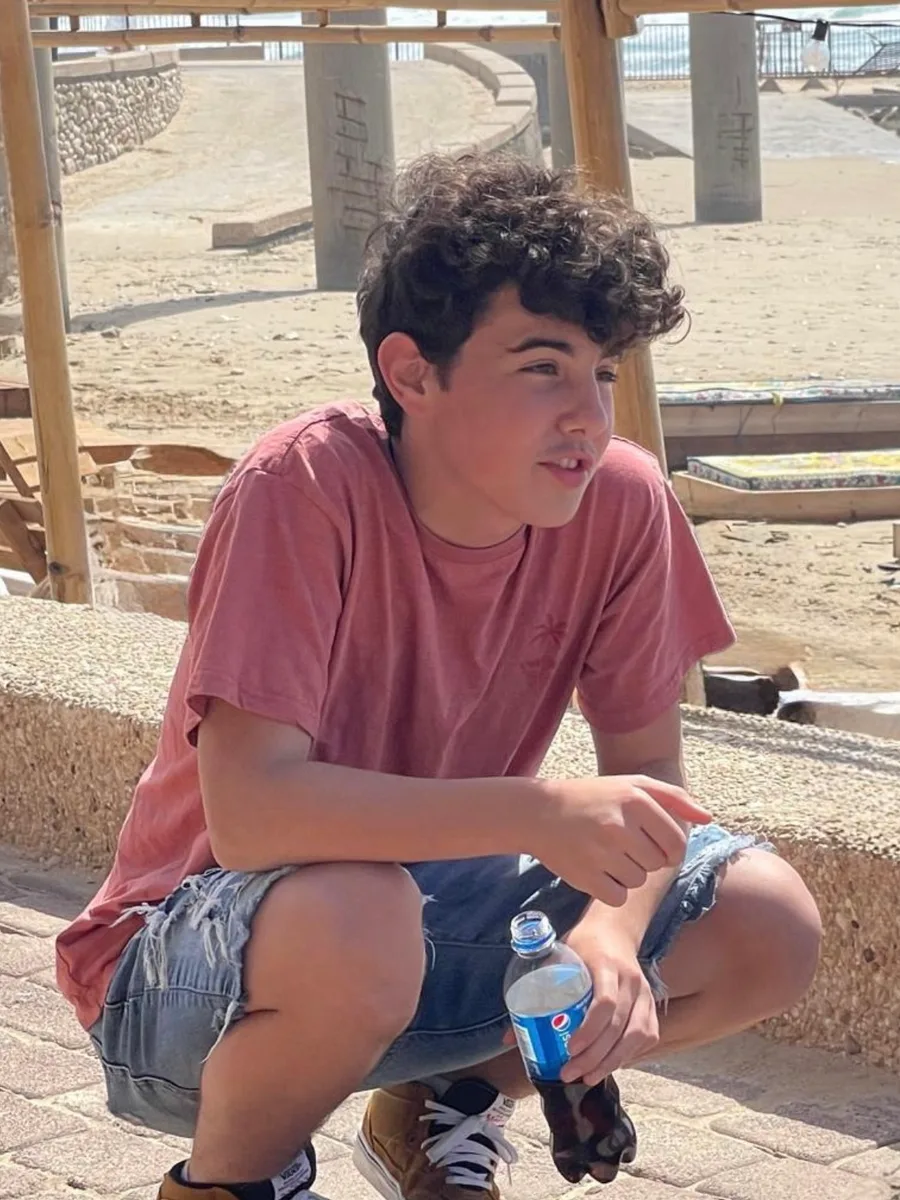 עומר כורע ליד הים בחולצה אדומה